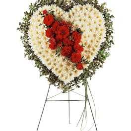 Heart-shaped funeral wreath with red and white flowers on a stand