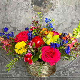 Colorful mixed flower arrangement in a gold vase with a red heart accent