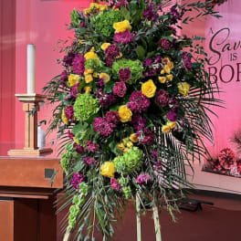 Tall standing floral spray with yellow and purple blooms on an easel