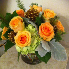 Orange roses arranged with green hydrangea in a glass vase