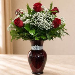 Red roses and white baby's breath in a dark glass vase