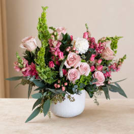 Pink roses and mixed blooms arranged in a white vase