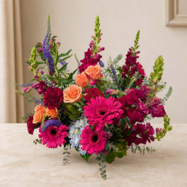 Mixed bouquet with pink gerbera daisies, peach roses, and purple spikes