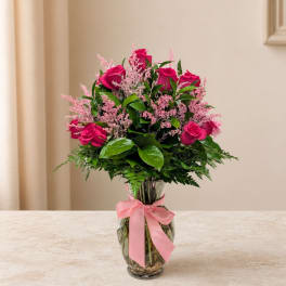 Pink roses in a clear glass vase with a pink ribbon
