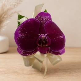 Purple orchid corsage with cream ribbon on a table