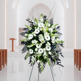 White floral standing spray with lilies and daisies on an easel