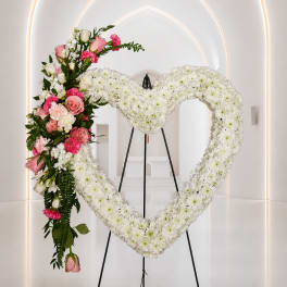 Heart-shaped floral wreath with white and pink flowers on a stand