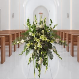 Tall white and green floral arrangement in a church aisle