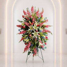 Tall standing floral arrangement with pink, white, and blue flowers on a metal easel