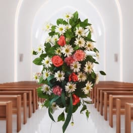 Floral spray with white daisies and coral roses in a church aisle