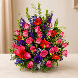 Bright mixed bouquet of pink roses, purple blooms, and orange flowers in a vase