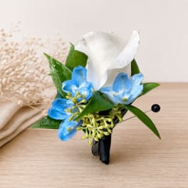 Small white and blue floral boutonniere with green leaves
