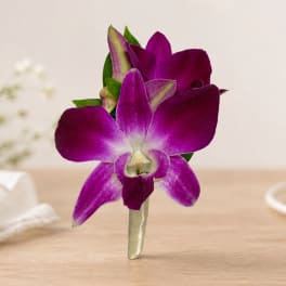 Purple orchid boutonniere with green accents on a wrapped stem