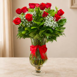 Red roses in a clear glass vase with a red ribbon