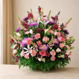 Large mixed flower arrangement in a basket with pink, purple, and white blooms