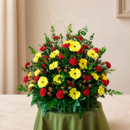 Large red and yellow floral arrangement in a low container