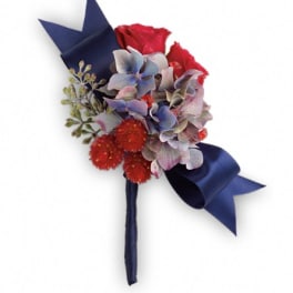 Boutonniere with red roses, blue hydrangea, and navy ribbon