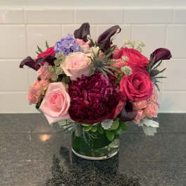 Mixed pink and purple flower arrangement in a glass vase