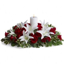 Red roses and white lilies arranged around a white candle