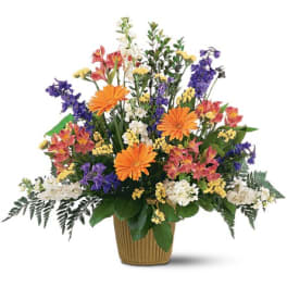 Mixed bouquet in a ribbed basket with orange, purple, white, and yellow flowers