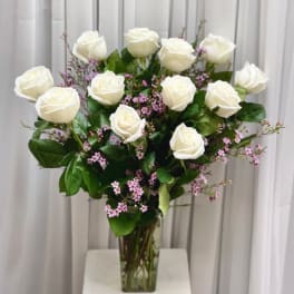 White roses and pink filler flowers in a clear glass vase