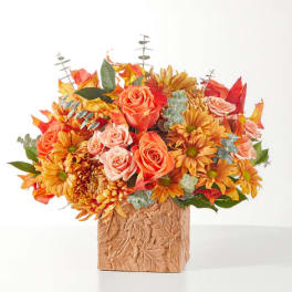 Orange and peach flowers in a leaf-patterned square vase