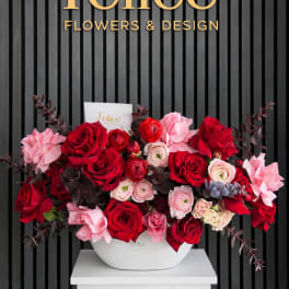 Red and pink rose arrangement in a white vase