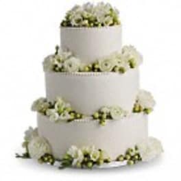 Four-tier white wedding cake with white flowers around each layer