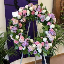 Large floral wreath on an easel with pink, white, and lavender flowers
