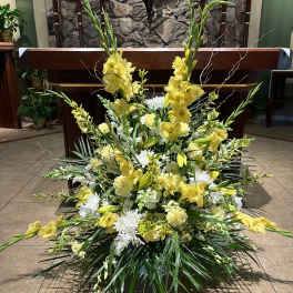 Large yellow and white floral arrangement in front of an altar