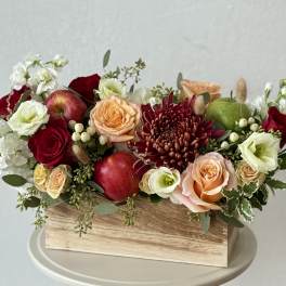 Mixed flower arrangement in a wooden box with apples and roses
