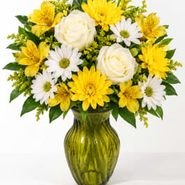 Yellow and white flowers arranged in a green glass vase