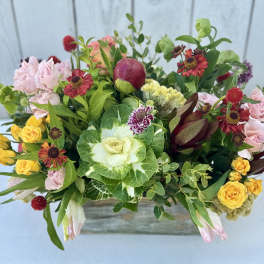 Mixed bouquet with pink and yellow roses in a low wooden container