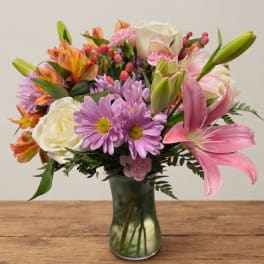 Mixed bouquet of pink, white, and orange flowers in a glass vase