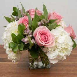 Pink roses and white hydrangeas arranged in a clear glass vase