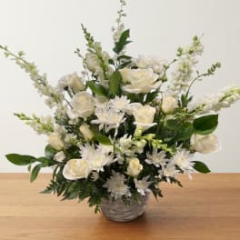 White roses and daisies arranged in a gray basket vase