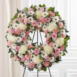 Pink and white floral wreath on a black stand