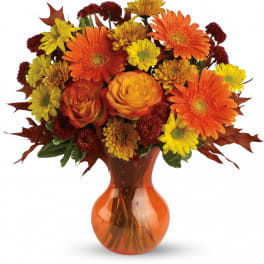 Orange and yellow mixed bouquet in an orange glass vase