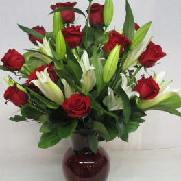 Red roses and white lilies arranged in a dark glass vase