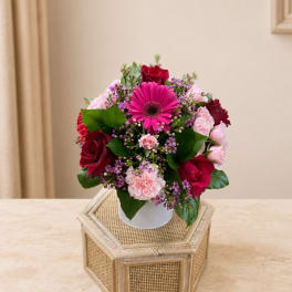 Pink and red mixed flower arrangement in a white vase