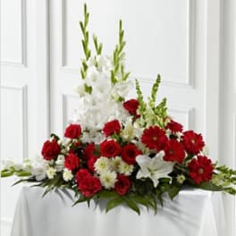 Red and white floral arrangement with tall white blooms in a low container