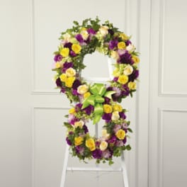 Floral standing wreath with yellow, purple, and white flowers on an easel