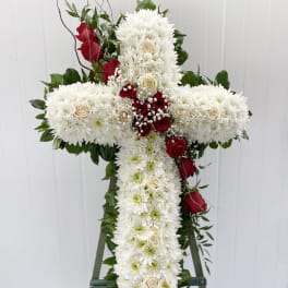 White floral cross with red roses on an easel