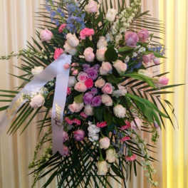 Large standing floral spray with pink, purple, and white blooms on a ribboned easel