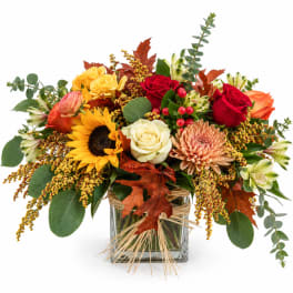 Autumn bouquet with roses, sunflower, chrysanthemum, and a glass vase