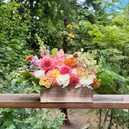 Mixed pink and peach flowers arranged in a wooden box
