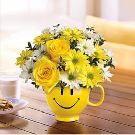 Yellow and white flowers in a smiley-face mug vase