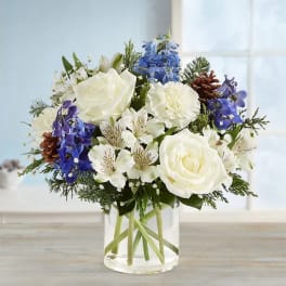 White and blue mixed bouquet in a clear glass vase