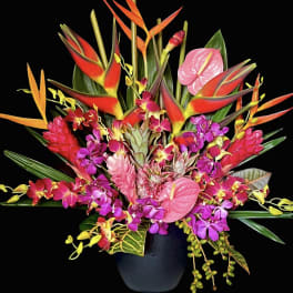 Tropical flower arrangement in a black vase with pink anthuriums and orchids