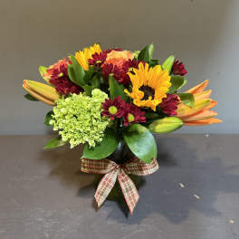 Mixed bouquet in a dark vase with a plaid ribbon